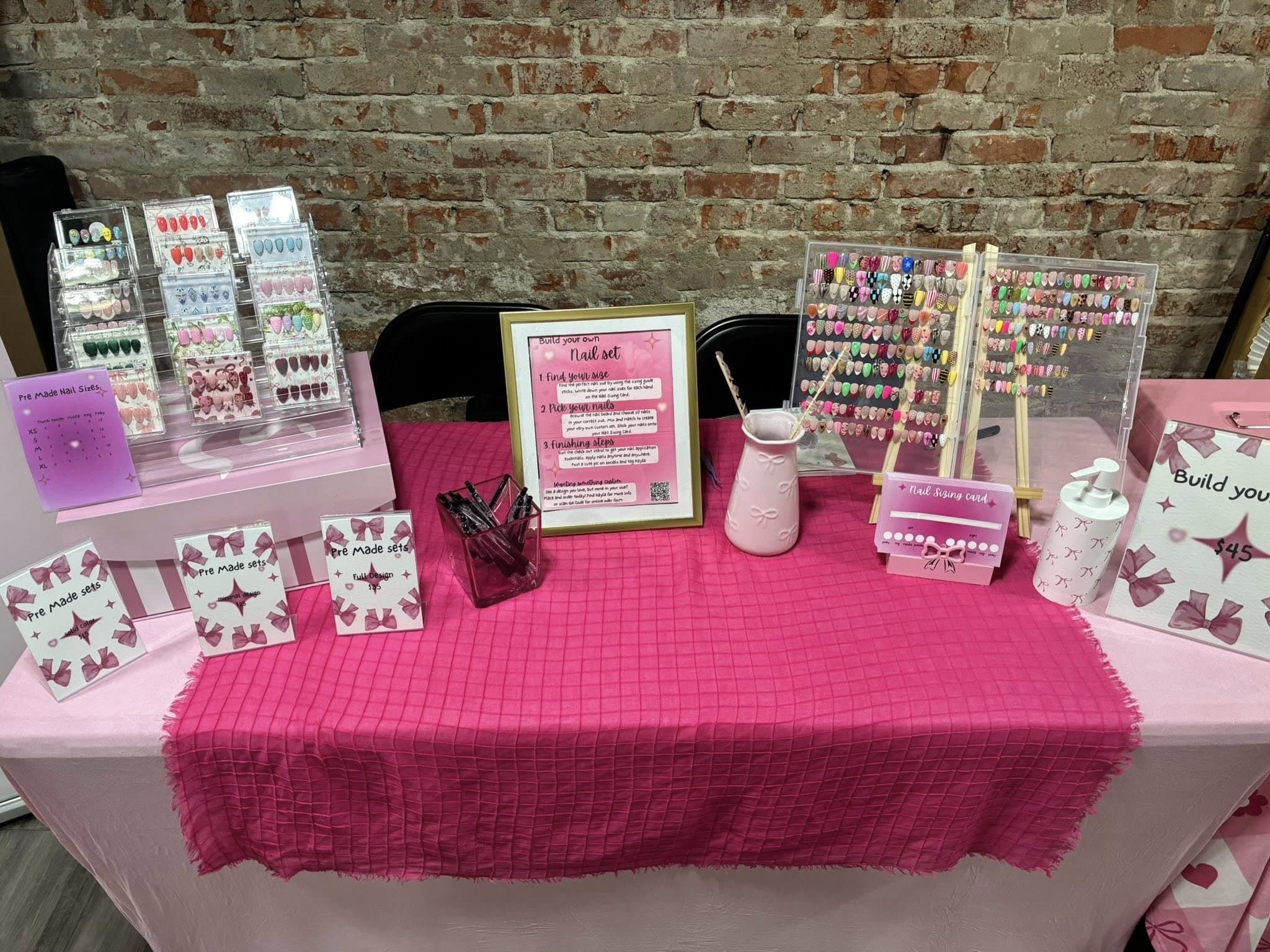 Custom Nails by Kayla booth table with pre-made sets and sizing cards